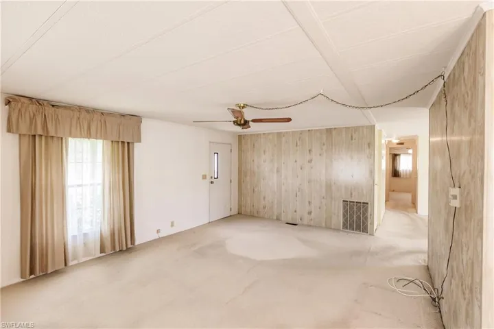 Unfurnished room with carpet, ceiling fan, and wood walls