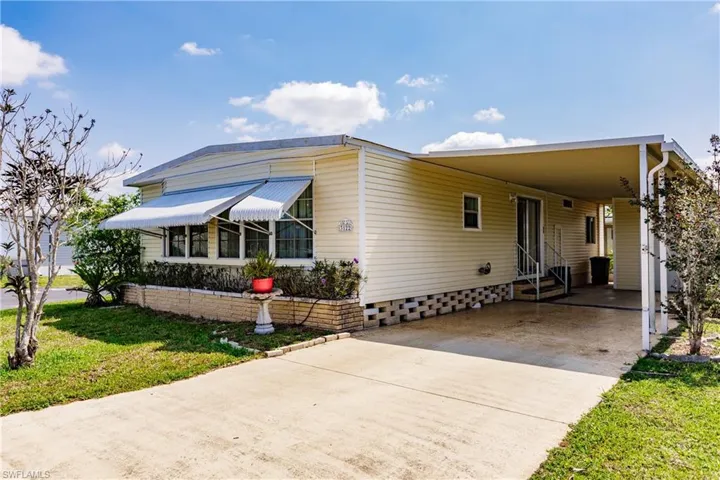 Manufactured / mobile home with a front yard and a carport
