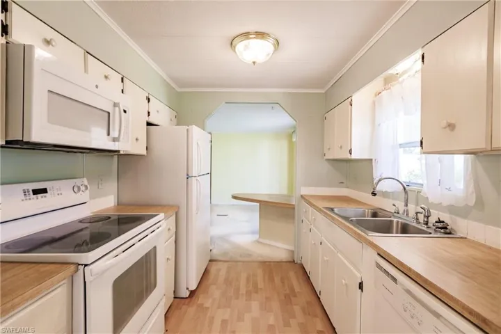 Kitchen featuring white appliances, sink, white cabinets, and light wood-type flooring