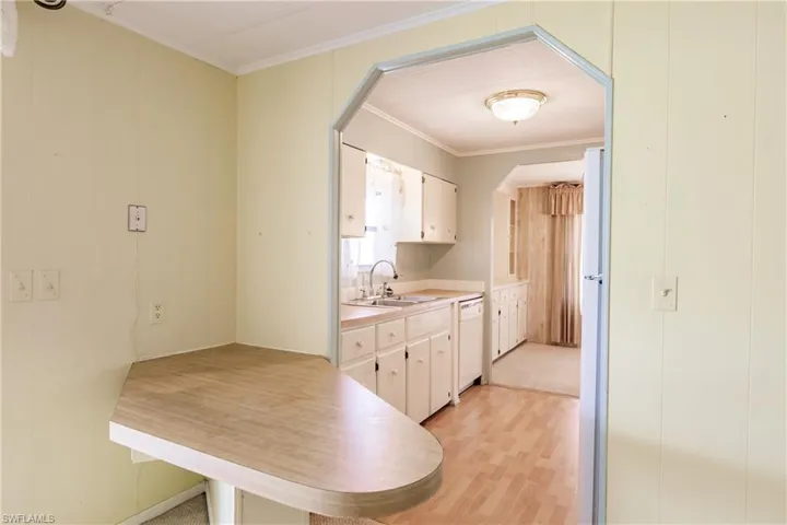 Kitchen featuring white cabinetry, sink, white appliances, and light hardwood / wood-style flooring