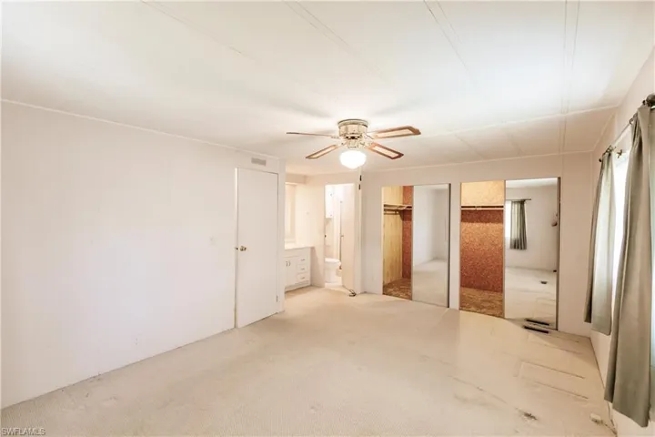 Unfurnished bedroom featuring connected bathroom, ceiling fan, and carpet floors