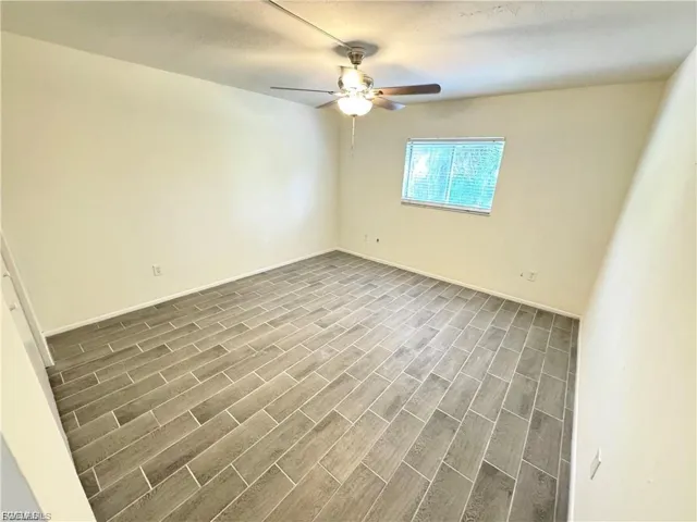 Spacious room featuring wood-finish tile flooring, a ceiling fan with integrated lighting, and a window with horizontal blinds