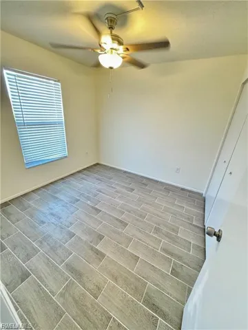 Recessed window with horizontal blinds, overhead ceiling fan with integrated lighting, and tile flooring
