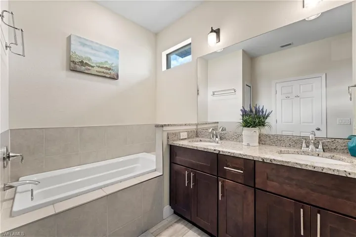 Full bath with a bath, double vanity, a sink, and visible vents