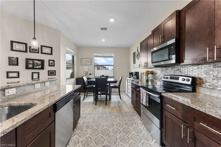 Kitchen with visible vents, appliances with stainless steel finishes, dark brown cabinetry, light stone countertops, and decorative backsplash