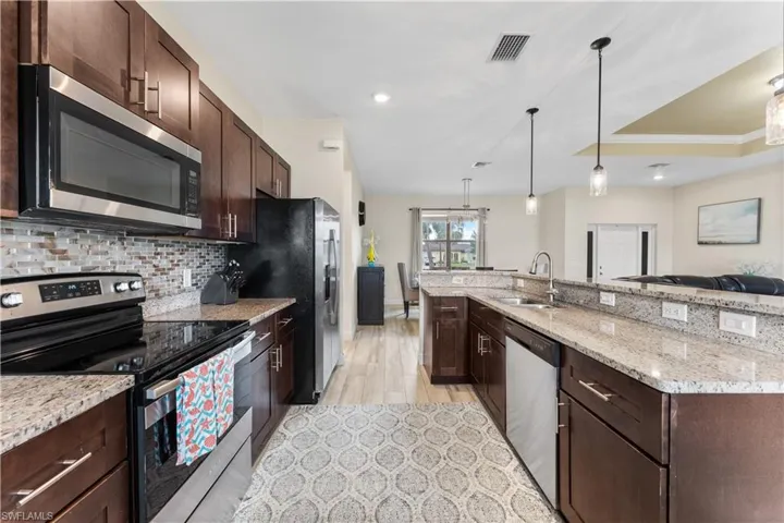 Kitchen featuring visible vents, a sink, appliances with stainless steel finishes, dark brown cabinetry, and backsplash
