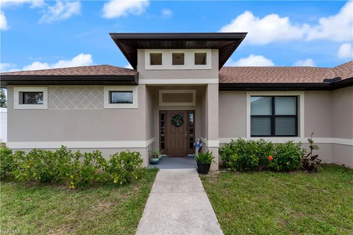 Doorway to property featuring a yard and stucco siding