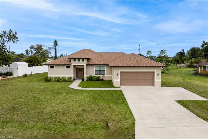 View of front of home with an attached garage, concrete driveway, fence, stucco siding, and a front lawn