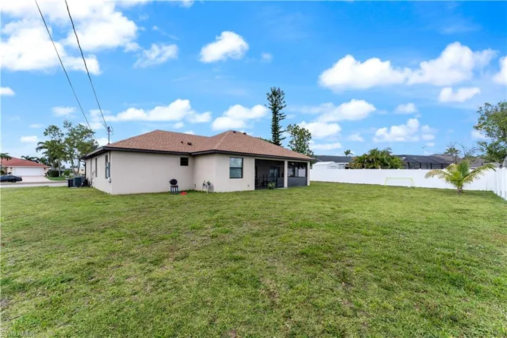 Rear view of house featuring a yard, a fenced backyard, a sunroom, and stucco siding