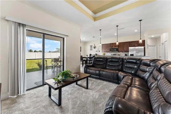 Living area featuring ornamental molding, recessed lighting, and a tray ceiling