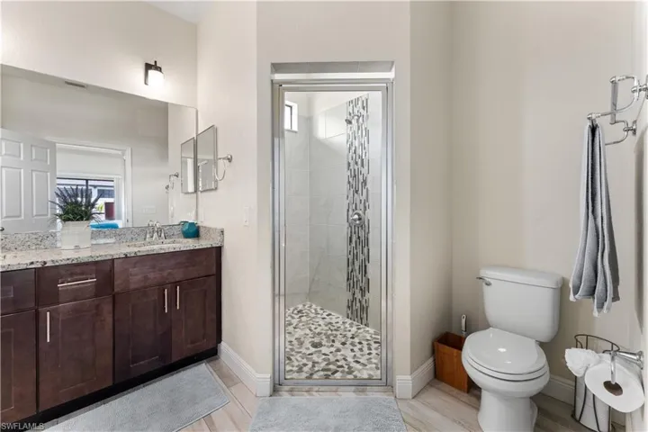 Bathroom featuring a shower stall, vanity, baseboards, and toilet