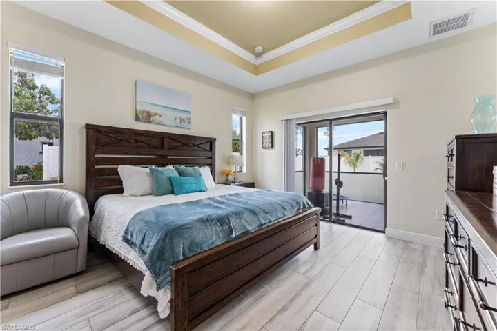 Bedroom with visible vents, access to exterior, a raised ceiling, and light wood-style floors