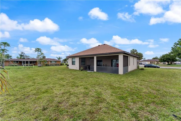 Back of property featuring stucco siding, a sunroom, and a lawn