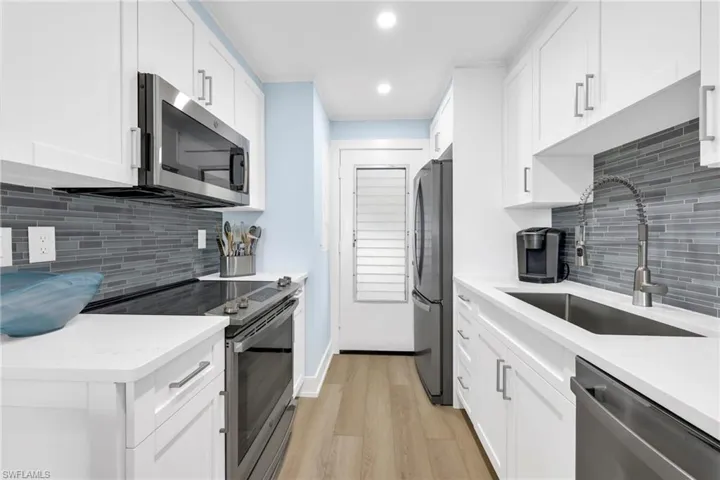 Kitchen with stainless steel appliances, tasteful backsplash, light wood-style floors, light countertops, and recessed lighting