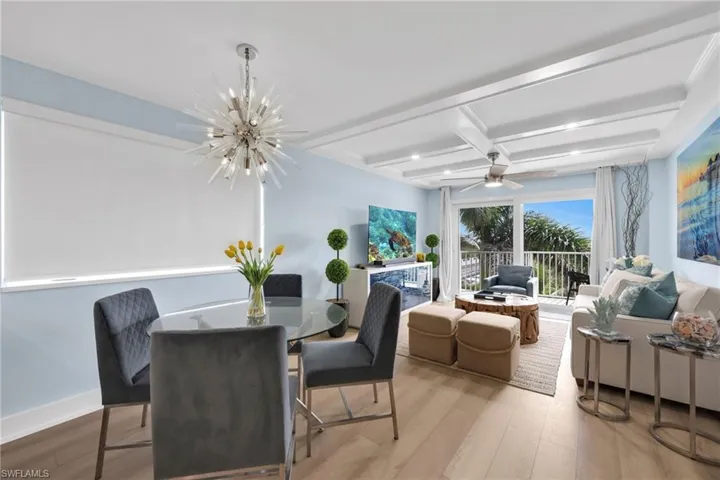 Dining area featuring a chandelier, wood finished floors, beam ceiling, coffered ceiling, and a ceiling fan