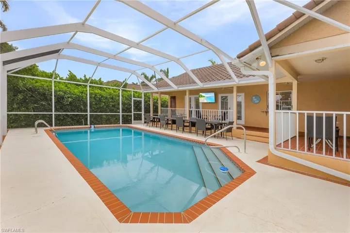 View of swimming pool featuring glass enclosure and a patio