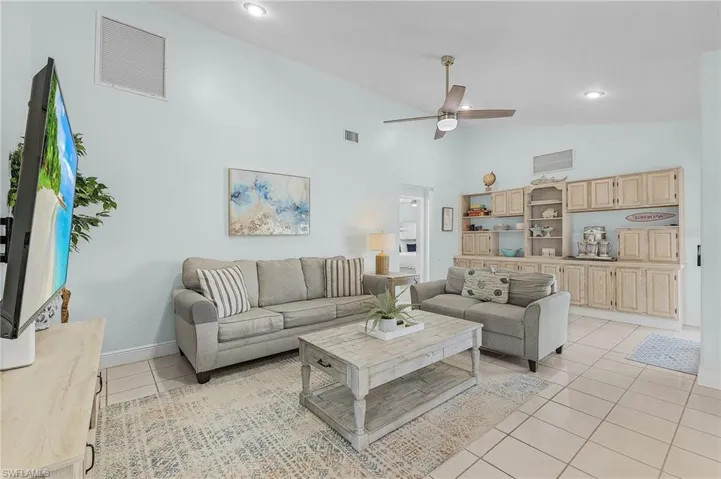 Living room with ceiling fan, light tile patterned floors, and high vaulted ceiling
