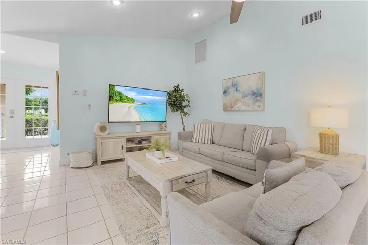 Tiled living room with high vaulted ceiling and ceiling fan