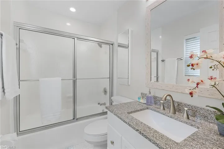 Full bathroom with shower / bath combination with glass door, vanity, and toilet