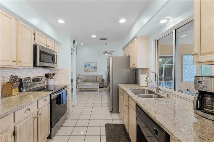 Kitchen featuring ceiling fan, light tile patterned flooring, sink, appliances with stainless steel finishes, and light brown cabinetry