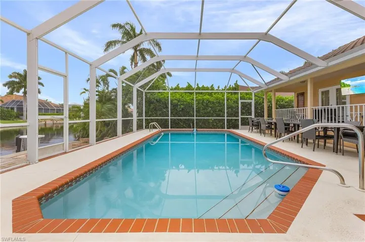 View of swimming pool featuring a water view, glass enclosure, and a patio