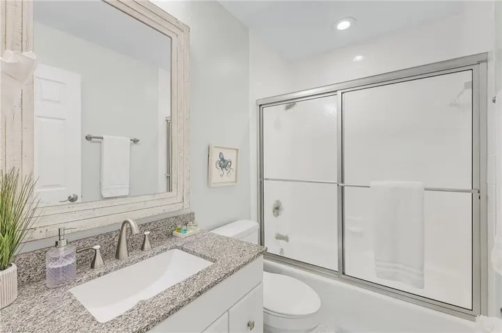 Full bathroom featuring bath / shower combo with glass door, vanity, and toilet
