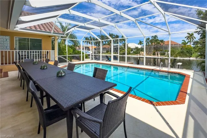 View of swimming pool featuring a water view, a patio area, and glass enclosure