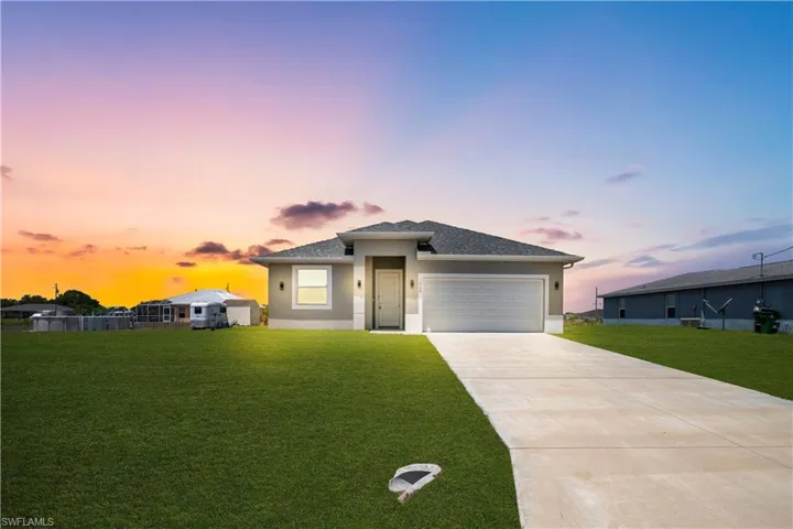 Contemporary single-story residence featuring a two-car garage, a concrete driveway, and a well-maintained lawn