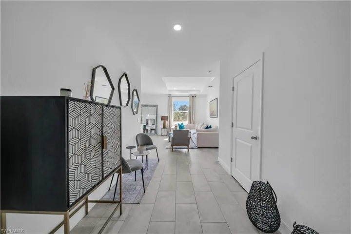 Bright entry hall featuring neutral tone tile flooring and recessed lighting