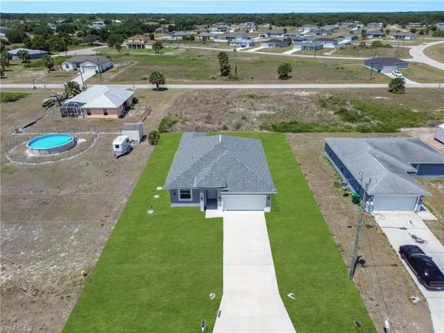 Newly constructed residence featuring a gray exterior, a dark shingle roof, and a front-facing garage