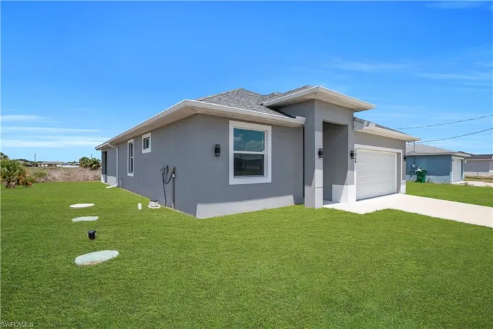 Contemporary stucco home with a two-car garage, concrete driveway, and covered front entry