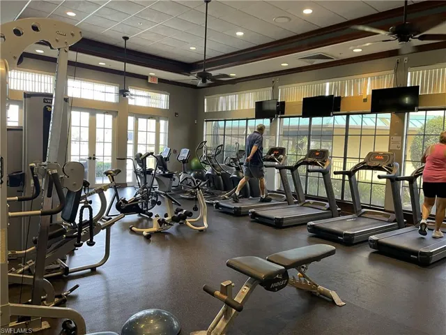 Exercise room featuring ceiling fan, a high ceiling, and recessed lighting