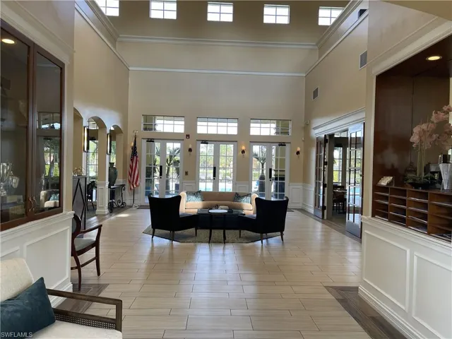 Community lobby featuring a decorative wall, a high ceiling, wainscoting, and crown molding