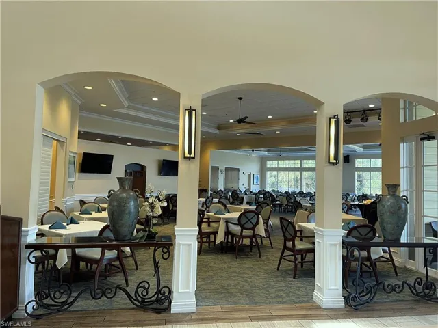 Dining room featuring arched walkways, wood finished floors, crown molding, ceiling fan, and a raised ceiling