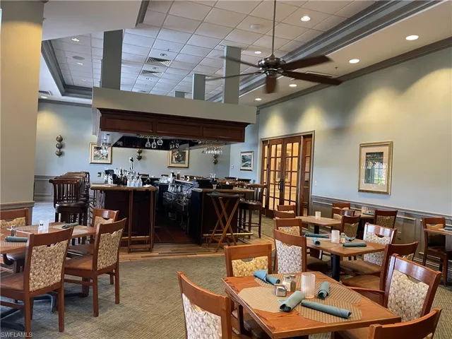 Dining room with a community bar, wainscoting, french doors, a towering ceiling, and ornamental molding