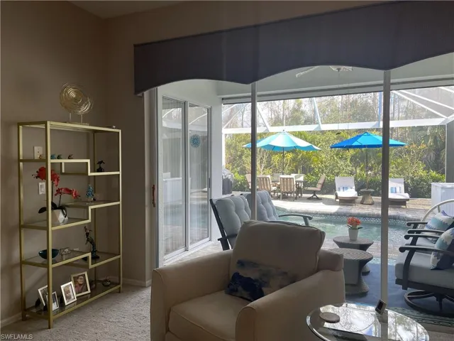Living room with sliders leading to expanded lanai with hurricane shutter