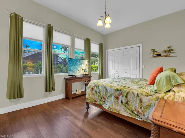 Bedroom featuring access to exterior, high vaulted ceiling, and wood finished floors