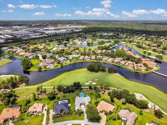 Aerial view of property and surrounding area featuring nearby suburban area, a local golf course, and a nearby body of water