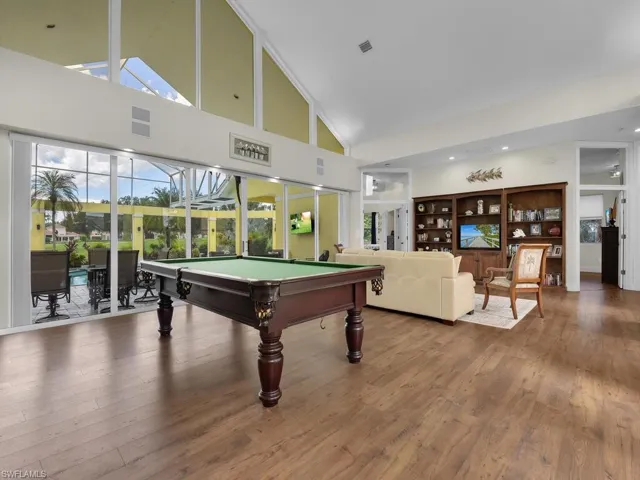 Sunroom featuring high vaulted ceiling, wood-type flooring, and a chandelier