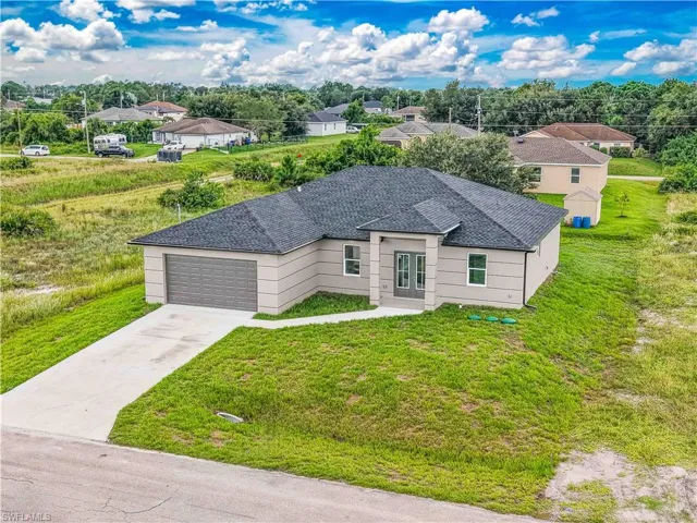 View of front of home featuring driveway, roof with shingles, a front lawn, an attached garage, and stucco siding