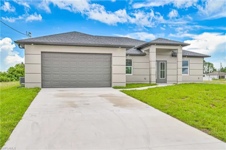 Prairie-style home featuring stucco siding, a front lawn, concrete driveway, and a shingled roof