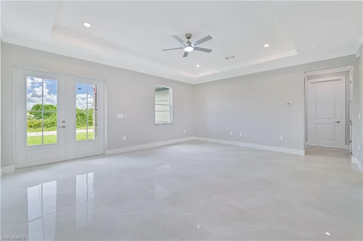 Unfurnished room with a raised ceiling, crown molding, french doors, recessed lighting, and a ceiling fan