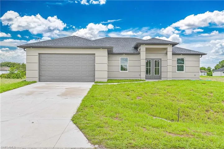 Prairie-style house with concrete driveway, a front yard, a shingled roof, a garage, and stucco siding