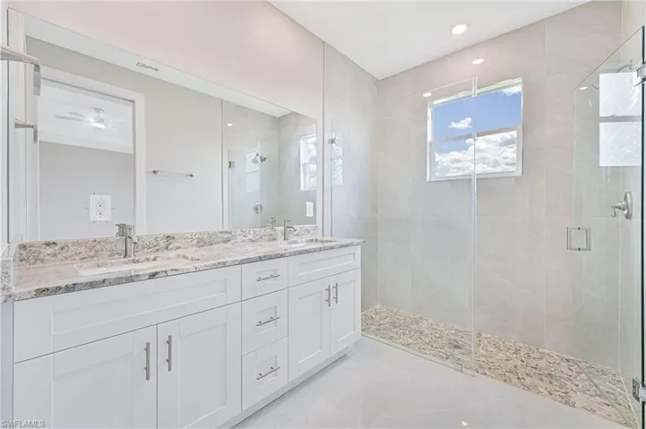 Full bathroom with a stall shower, double vanity, and light tile patterned floors