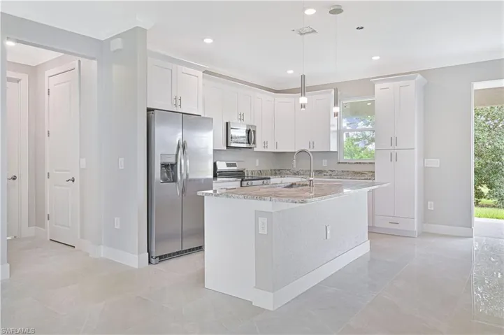 Kitchen with stainless steel appliances, crown molding, light stone counters, hanging light fixtures, and white cabinets