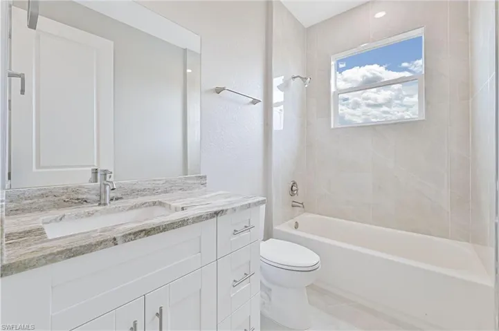 Full bath featuring bathing tub / shower combination, vanity, a textured wall, and light tile patterned floors