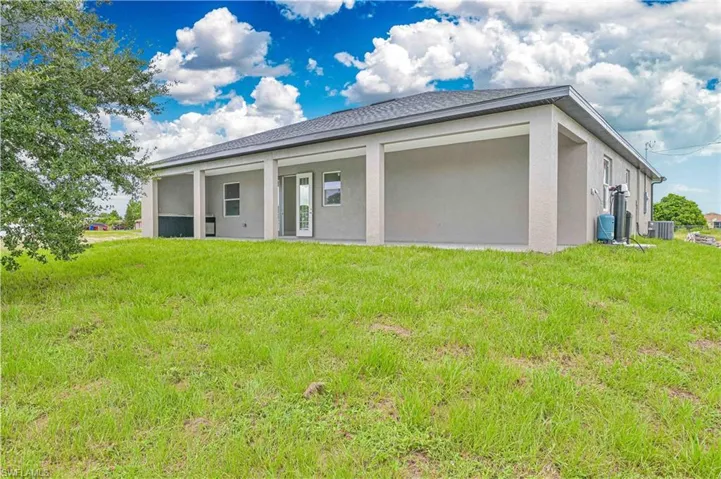 Back of property with stucco siding and a lawn