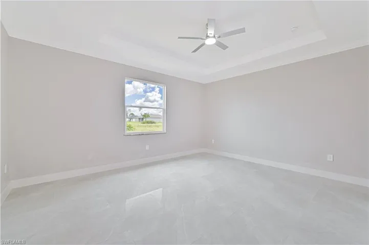 Unfurnished room with a raised ceiling, crown molding, and a ceiling fan