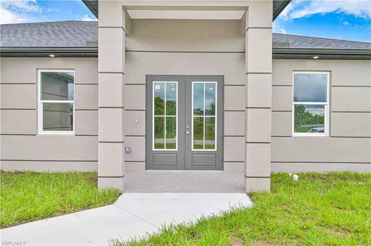 Entrance to property with a shingled roof, french doors, and stucco siding