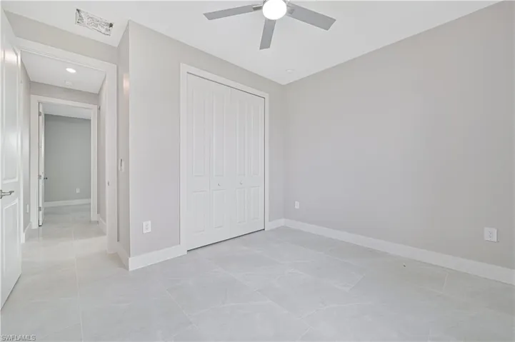 Unfurnished bedroom with a closet, a ceiling fan, and light tile patterned flooring